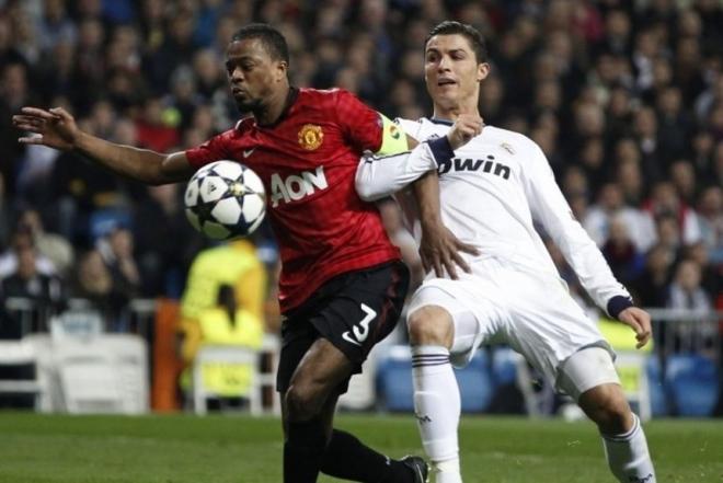 Patrice Evra pelea un balón con Cristiano Ronaldo en el Manchester United-Real Madrid de 2013.