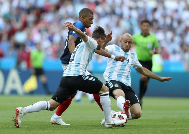 Kylian Mbappé lleva la pelota defendido por Tagliafico y Mascherano en el Francia-Argentina de octavos de final del Mundial.
