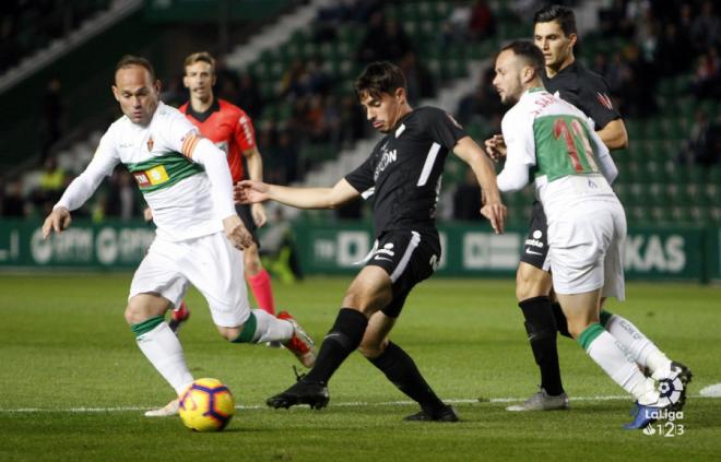 Carlos Cordero intenta despejar un balón ante Nino en el Elche-Sporting (Foto: LaLiga):