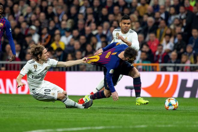 Luka Modric agarra a Leo Messi durante el Clásico Real Madrid-Barcelona.