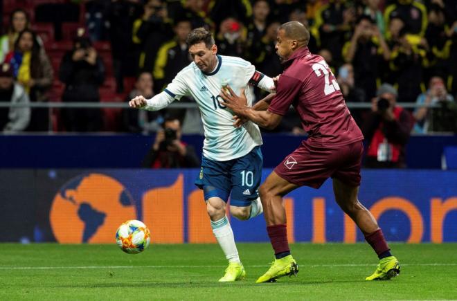 Messi pugna por un balón con un jugador venezolano.