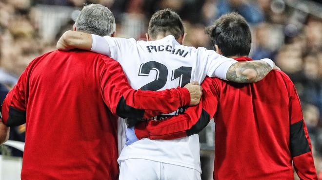 Piccini se marcha lesionado del Valencia-Levante ayudado por los médicos.