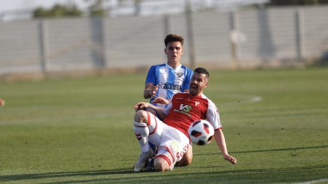 Hugo pelea un balón con un rival (Foto: Real Murcia/Carlos Guerrero).
