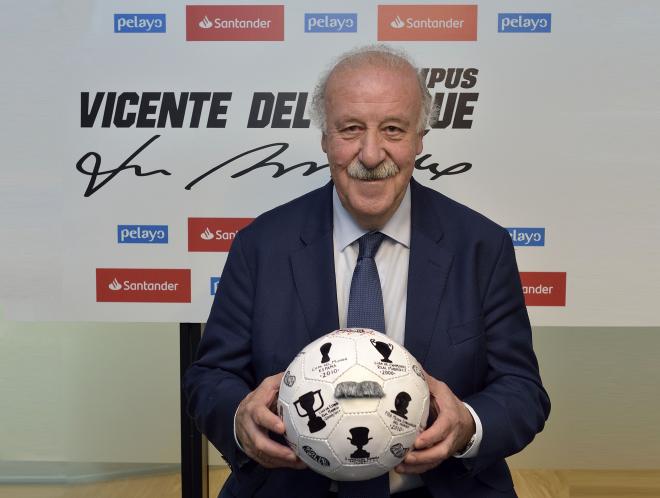 Vicente del Bosque firma su balón solidario en un acto.
