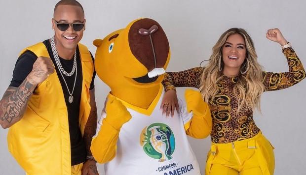 Leo Santana y Karol G posan con Zizito, la mascota de la Copa América 2019.