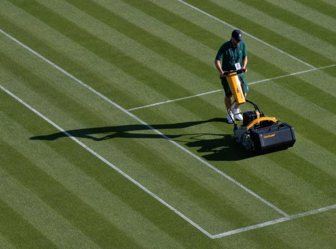 Un operario corta el césped de una de las pistas de tenis de Wimbledon.