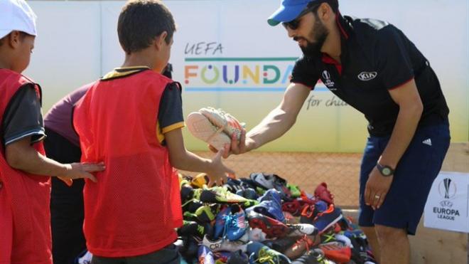 Un miembro de la Fundación de la UEFA, entrenando botas de futbol a los niños sirios (Foto: UEFA).