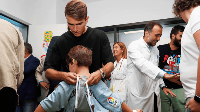 Denis Suárez ata el nudo de una bata a un pequeño aficionado en el hospital (RCCV).