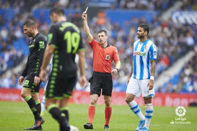 El colegiado muestra una amarilla durante el Real Sociedad-Betis del Reale Arena de la pasada temporada (Foto: LaLiga).