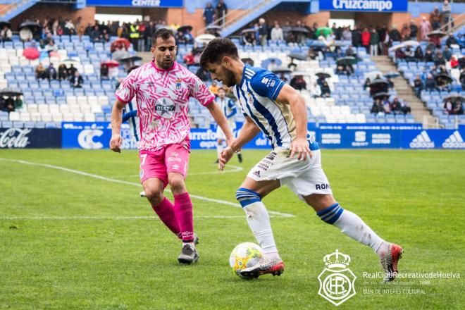 Carlos Martínez trata de regatear a un futbolista del CD Badajoz. (@recreoficial)