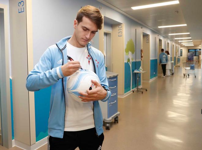 Denis Suárez estampa su firma en un balón durante la visita al hospital Álvaro Cunqueiro (Foto: RCCV).