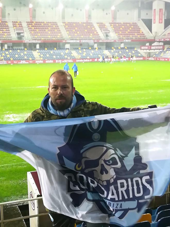 Daniel Pades posa con la bandera de la peña de la UD Ibiza en el Estadio de Pasarón.