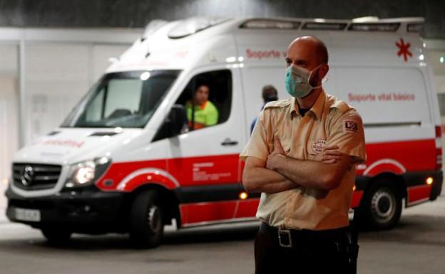 Una ambulancia llega al HUCA y un seguridad con una mascarilla contra el coronavirus (Foto: EFE).