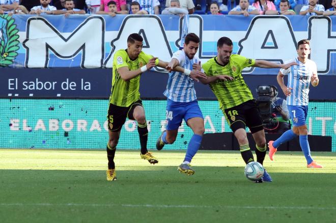 Luis Muñoz, entre dos jugadores del Zaragoza (Foto: Paco Rodríguez).