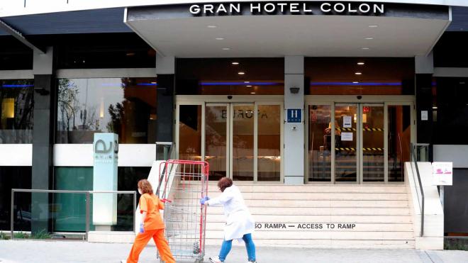 Dos empleadas con máscaras pasan por el hotel Gran Colon que acogerá pacientes con el virus COVID-19.