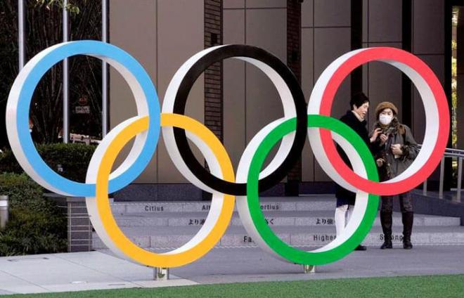 Dos individuos, en Tokio con mascarillas ante el icono de los Juegos Olímpicos.