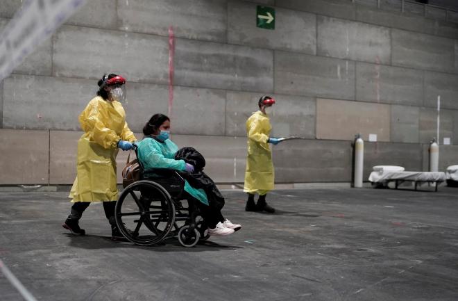 Una enfermera lleva a una paciente en silla de ruedas en el hospital de Ifema creado por la crisis del coronavirus.