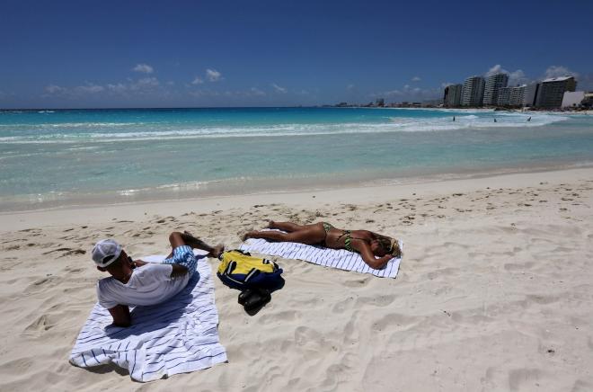 Vista de dos turistas tomando el sol en una playa de Cancún (Foto: EFE).