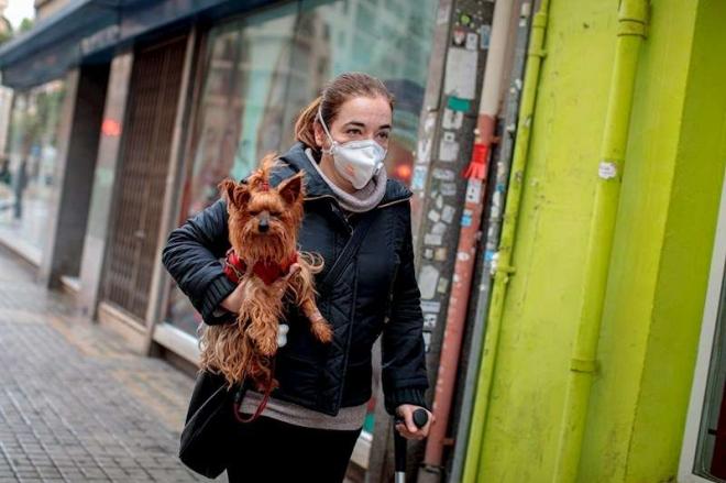 Una mujer con mascarilla y su perro durante la cuarentena del coronavirus (Foto: EFE)