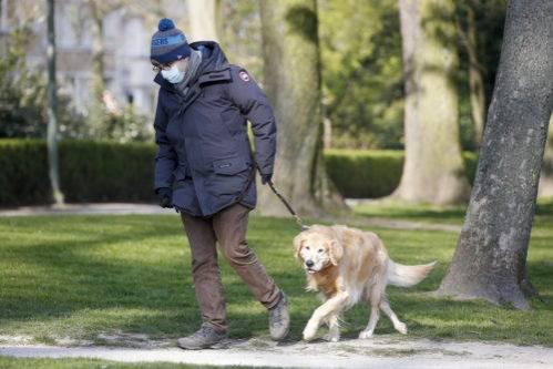 Un hombre utiliza medida de protección como las mascarillas para pasear con su perro por la ciudad.