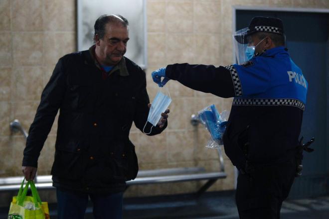 Un hombre coge una mascarilla de manos de un policía municipal en Valladolid (Foto: EFE).