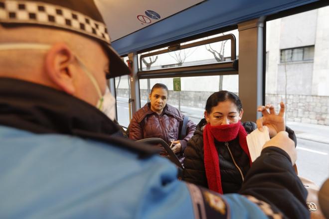 Un agente reparte mascarillas en un autobús.