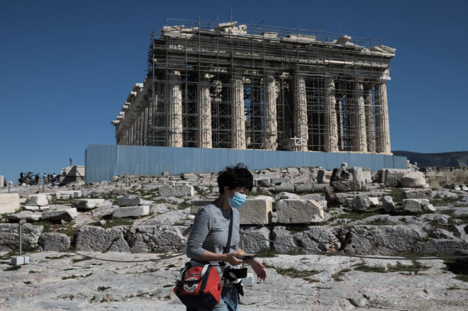 El Partenón de Grecia, con una ciudadana con mascarilla paseando por delante.