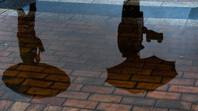 El reflejo de dos personas en los charcos de lluvia (foto: EFE).