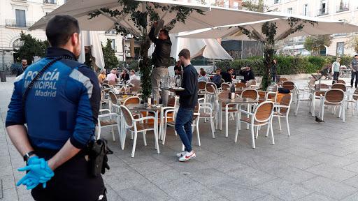 Terraza de uno de los bares madrileños, vigilada por un Policía (Foto: EFE).