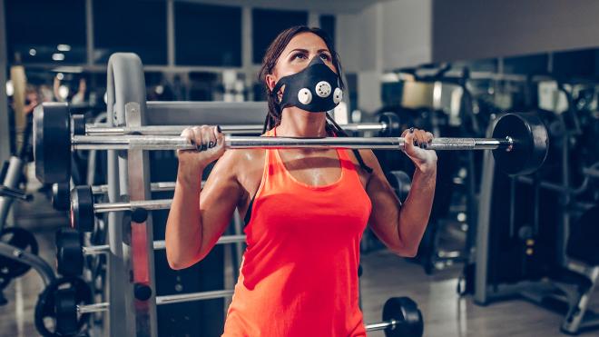 Una chica realiza trabajo físico en un gimnasio con mascarilla.