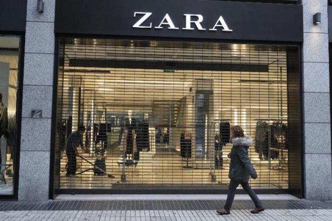 Una mujer pasa por delante del escaparate de una tienda Zara cerrada (Foto: EFE).