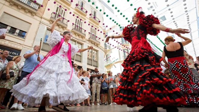 Dos mujeres bailan en plena calle Larios durante una pasada Feria de Málaga (Foto: EFE).