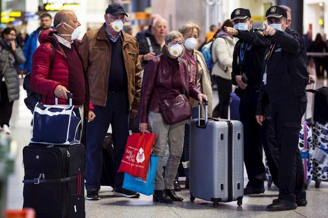 Policías dan instrucciones a unos viajeros en un aeropuerto durante la crisis del coronavirus.