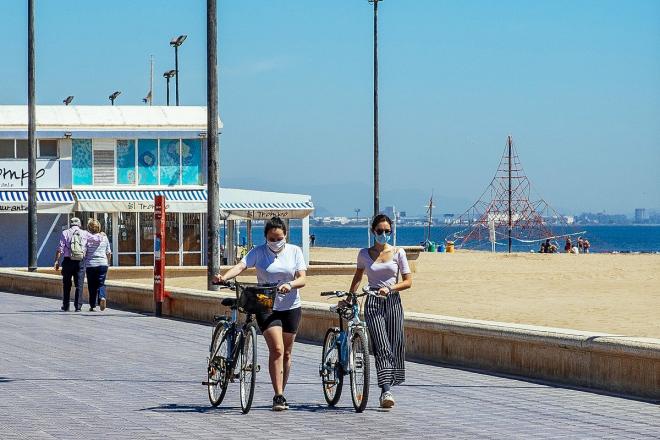 Ciclistas con mascarillas en la playa de Valencia