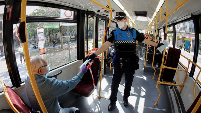 Un Policía Foral da una mascarilla a un ciudadano en un autobús de Pamplona.
