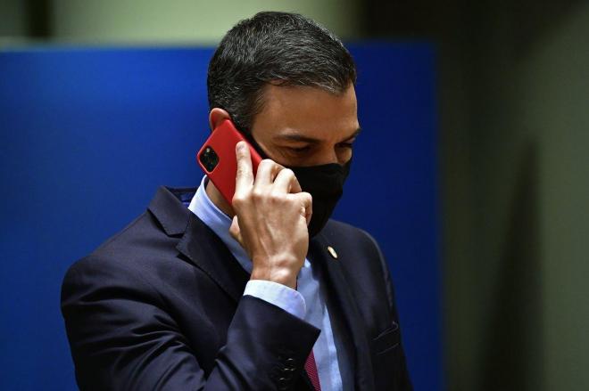 Pedro Sánchez, presidente del Gobierno, habla por el móvil con mascarilla (Foto: EFE/JOHN THYS).