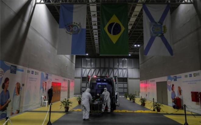 Dos médicos trasladan a un paciente con coronavirus en Brasil.