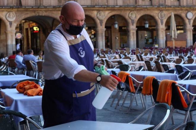 Un camarero en la Plaza Real de Barcelona desinfecta una mesa.