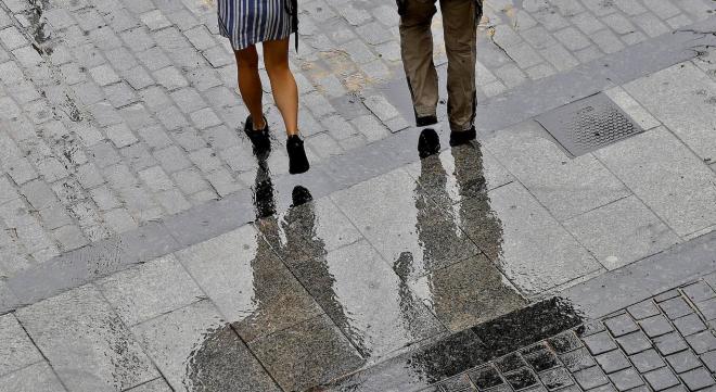 Dos personas caminan protegidos de la lluvia con paraguas. (Foto: EFE)