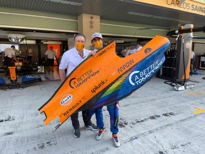 Zak Brown entrega a Carlos Sainz parte de la carrocería del monoplaza con el que compite (Foto: Mc