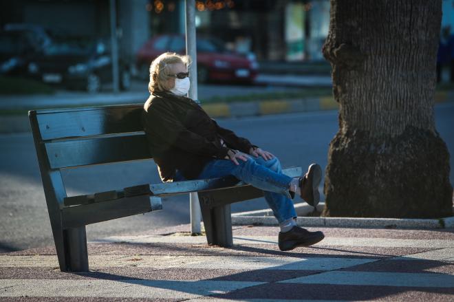 Una mujer descansa con mascarilla en un banco (Foto: EFE).