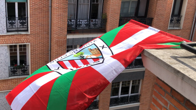 Una bandera con el escudo del Athletic Club sobre una ikurriña ondea en un balcón de Bilbao.