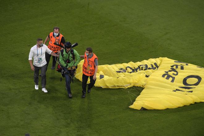 Los steward acompañan al paracaidista fuera del terreno de juego (Foto: Cordon Press).