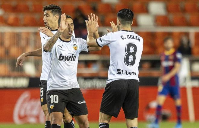 Carlos Soler, el 10 de la afición, se choca las manos con Cristian Oliva (Foto: Valencia CF).
