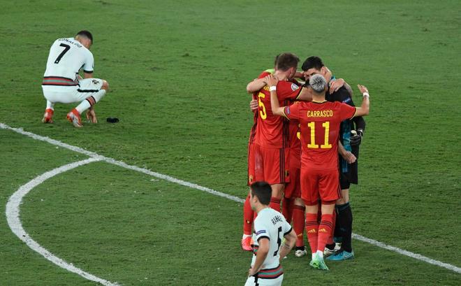 Los jugadores de Bélgica celebran la victoria mientras Cristiano Ronaldo se lamenta sobre el césp