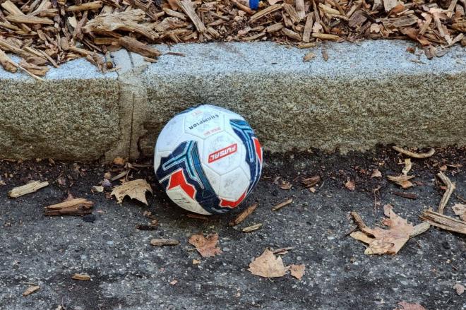 Un balón de fútbol tirado en la calle.