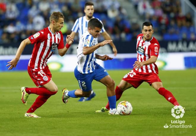Víctor Gómez trata de deshacerse de dos rivales en el Málaga-Lugo (Foto: LaLiga).