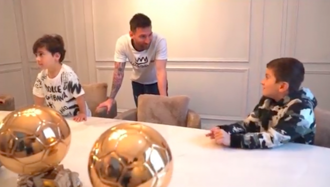Messi habla con su hijo Thiago con algún Balón de Oro en la mesa.