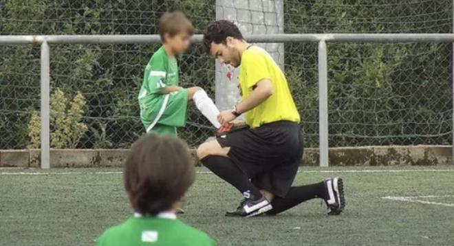 Lucas Vicente, joven árbitro fallecido, le ata los cordones a un niño durante un partido (Foto: T