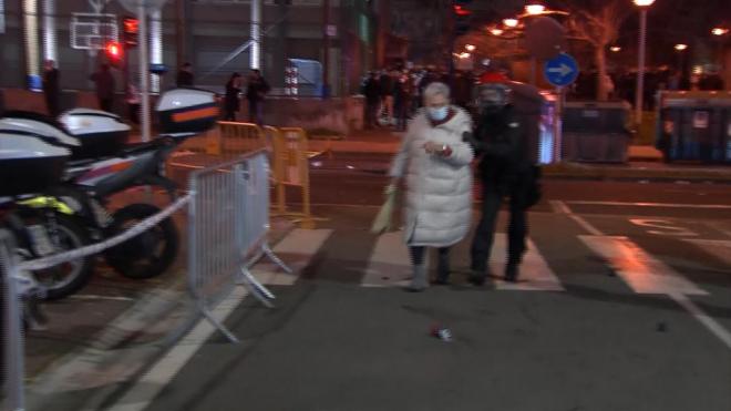 Un agente de la Ertzaintza retira a una señora de los disturbios en San Sebastián a la llegada del autobús del